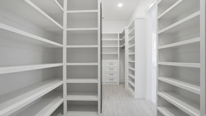 Expansive walk-in closet featuring built-in shelving, integrated drawer storage, a hanging rod, recessed lighting, and light-toned flooring