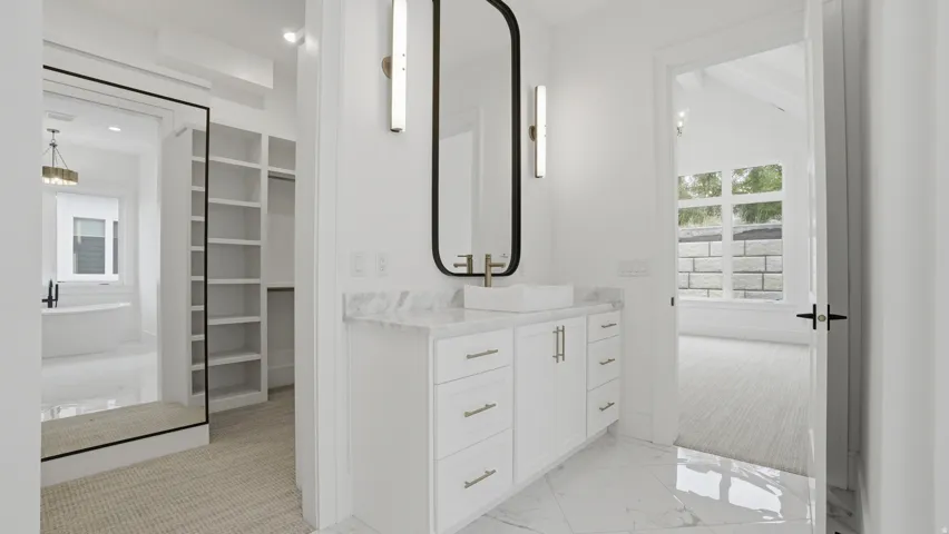 Contemporary vanity featuring a vessel sink with a wall-mounted faucet, a rectangular mirror, and sconce lighting