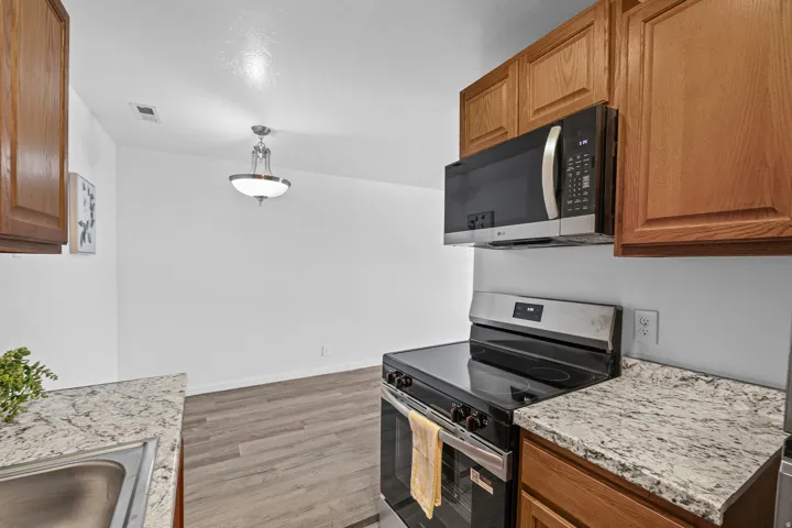 Kitchen featuring granite-style countertops, stainless steel appliances, and wood cabinetry
