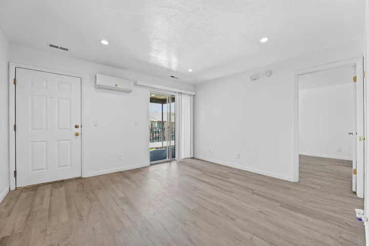 Open-concept living space with wood-finish flooring, white walls, and recessed lighting