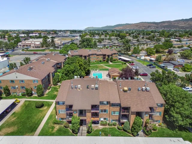 Aerial perspective showcasing multiple brick-clad apartment buildings with pitched shingle roofs