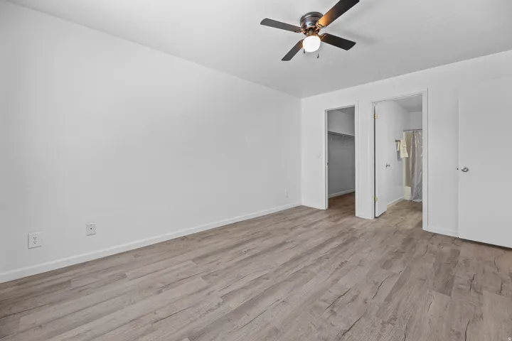 Interior room featuring vinyl wood-finish flooring, a ceiling fan with integrated lighting, and white baseboards
