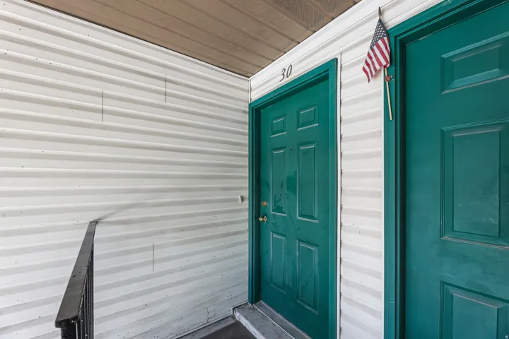 Entryway featuring white horizontal siding and a dark green paneled door