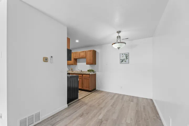 Open-concept living space with wood-finish flooring, a contemporary ceiling fixture, and bright white walls