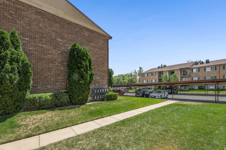 Brick exterior featuring green landscaping and a sidewalk