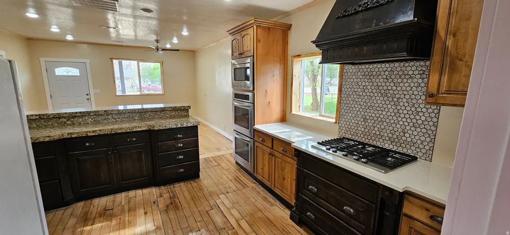 Spacious kitchen featuring rich wood cabinetry, stone countertops, a gas cooktop, and built-in stainless steel appliances