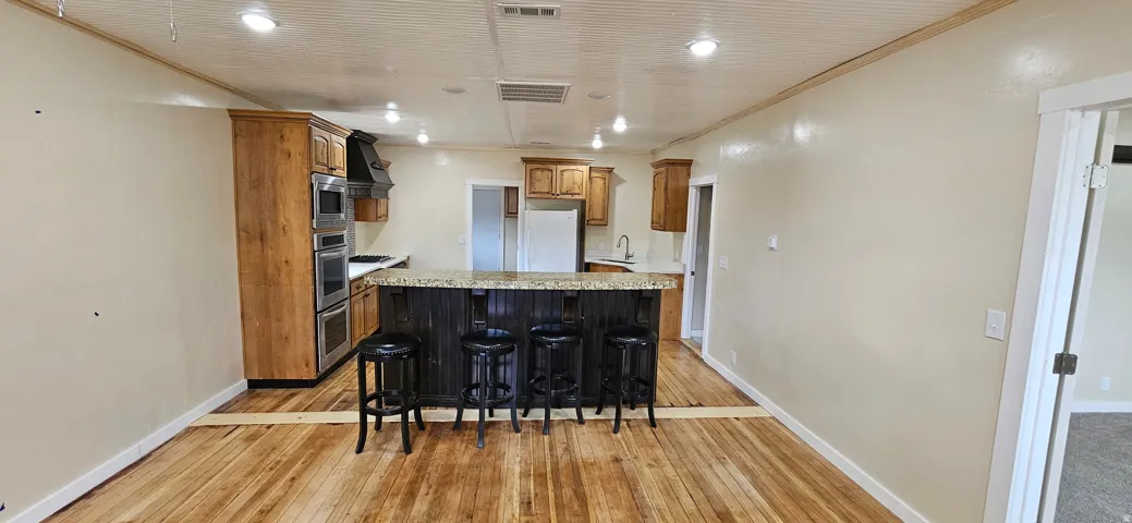 Open-concept kitchen and dining area featuring wood-finish flooring, recessed lighting, and a kitchen island with seating