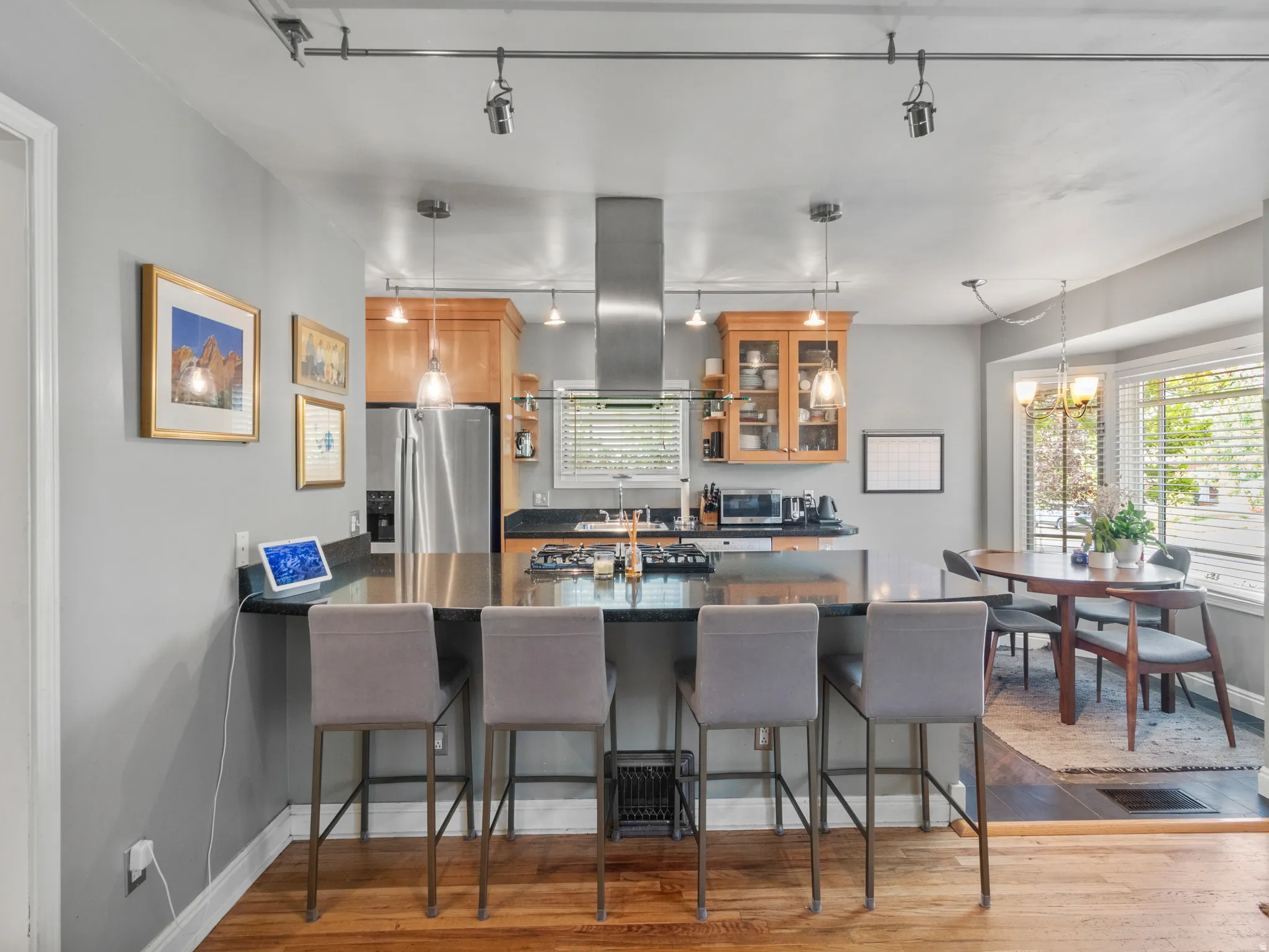 Kitchen featuring an eat-at island with a black countertop, stainless steel appliances, wood-finish cabinetry, and recessed lighting