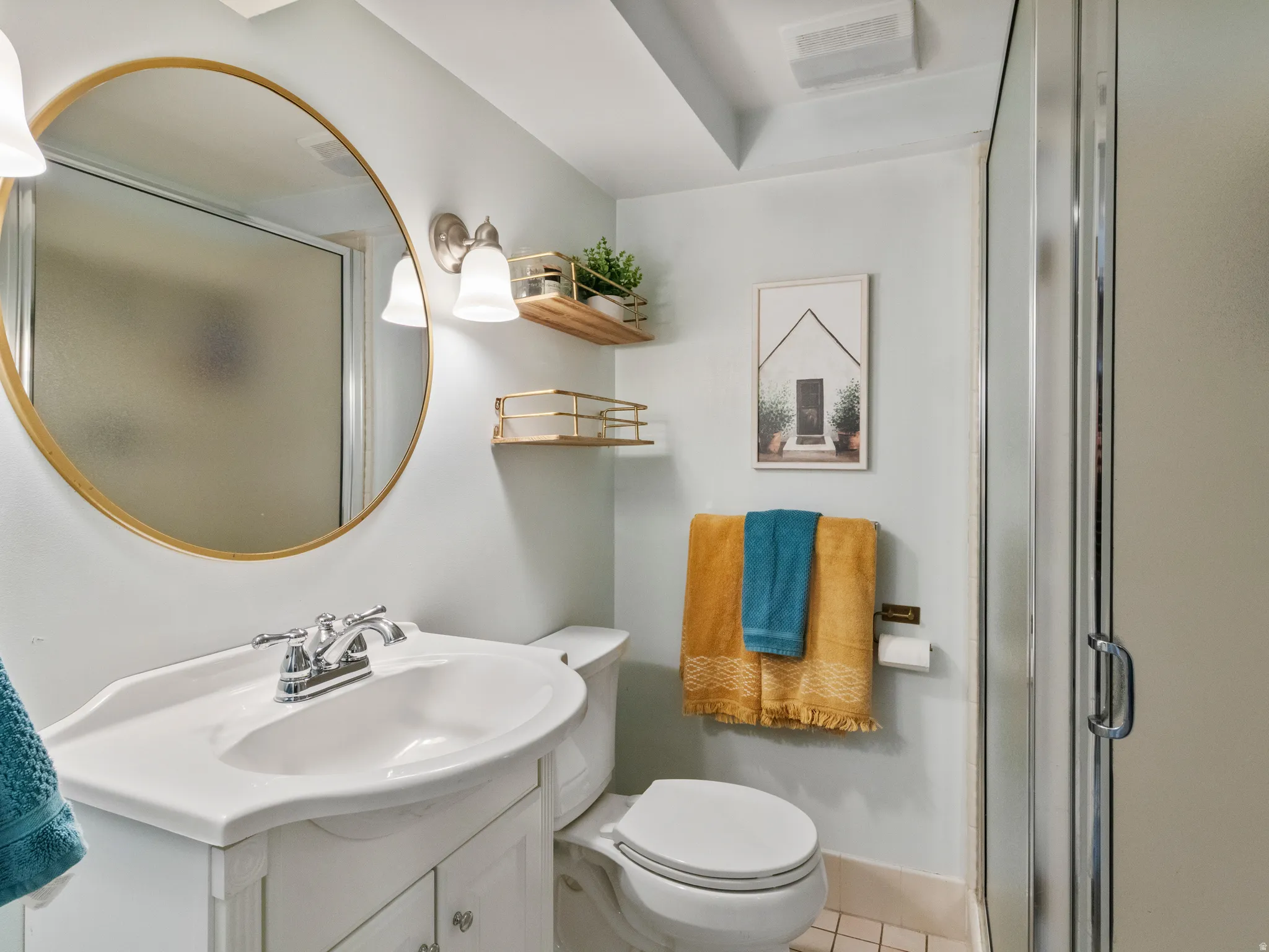 Bathroom featuring a glass-enclosed shower, white vanity with integrated sink, chrome faucet, wall-mounted light fixture, and a large round mirror