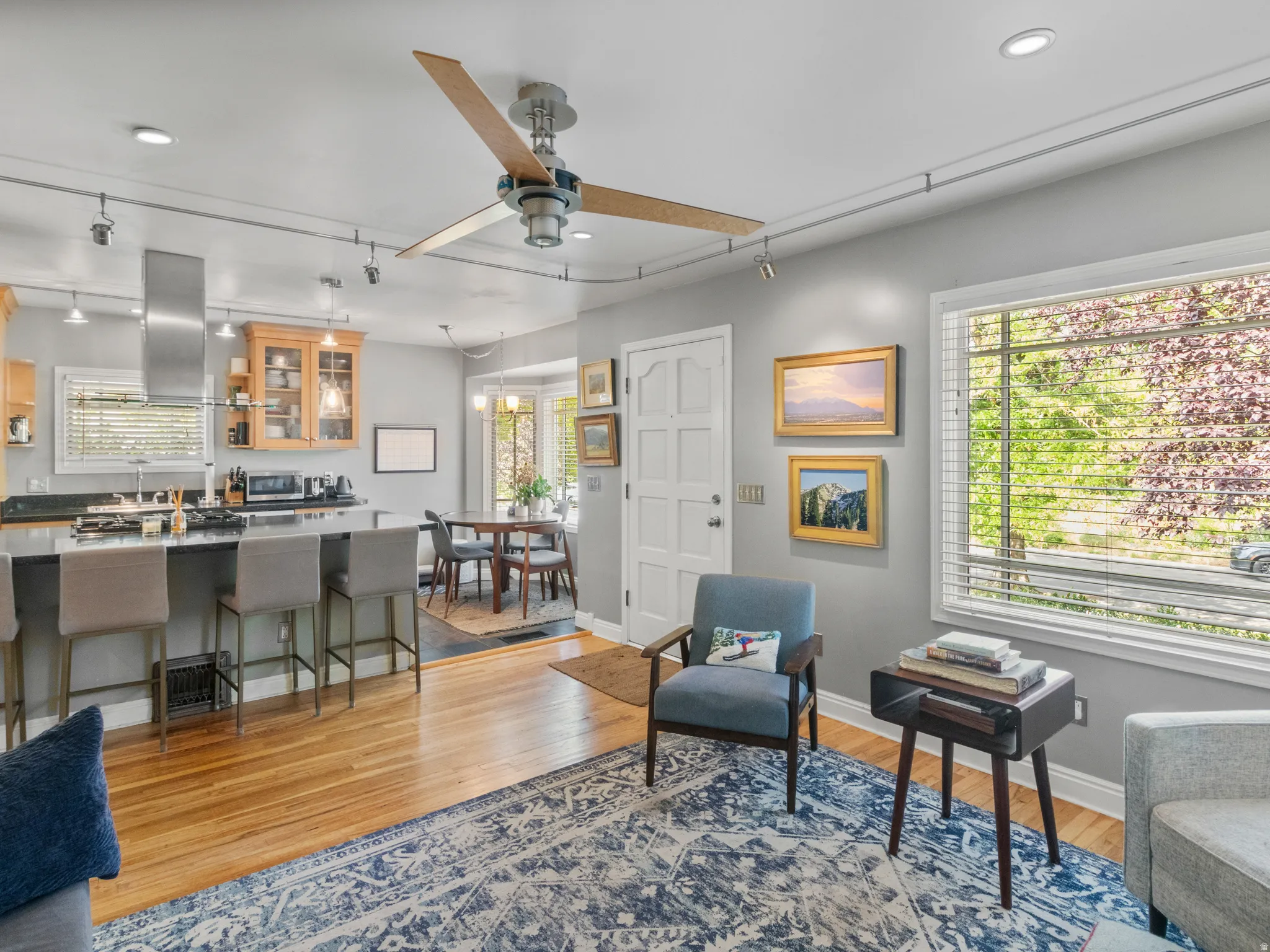 Open-concept living area featuring wood-finish flooring and a contemporary ceiling fan with track lighting