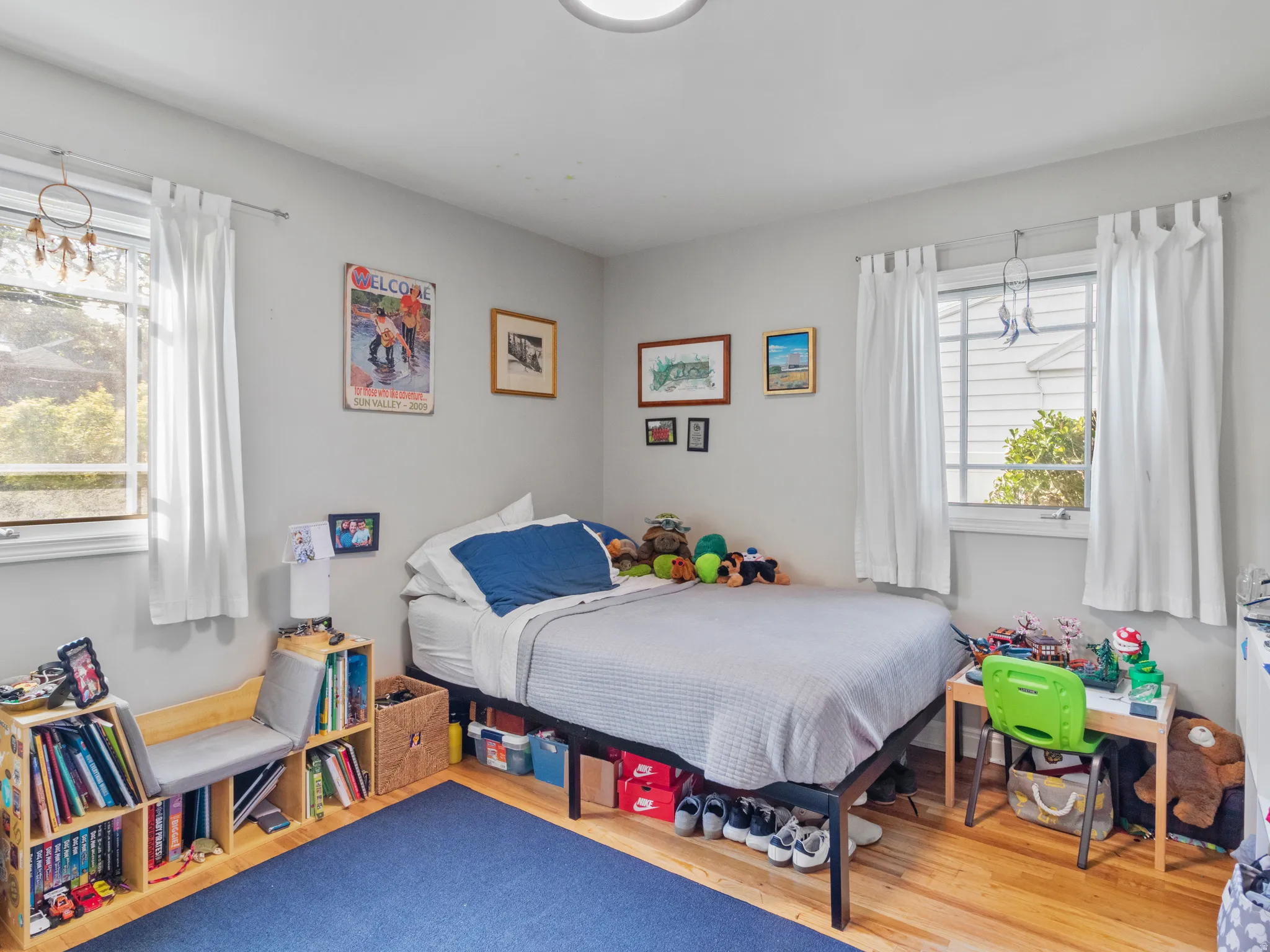 Light-filled room featuring wood-finish flooring, two large windows, and neutral wall tones