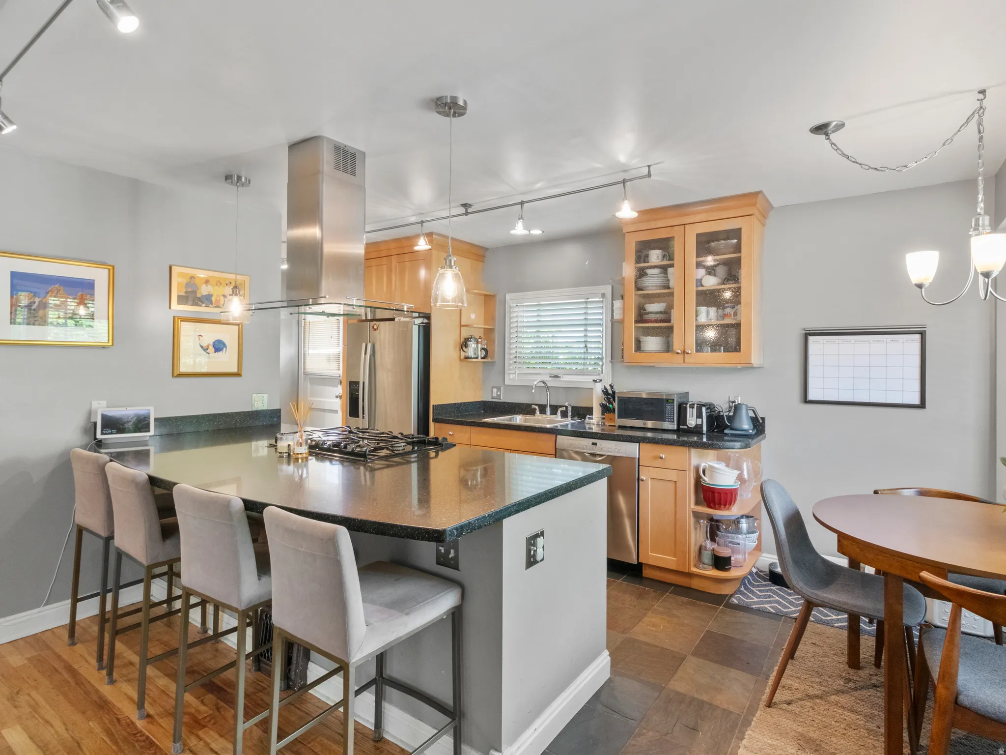 Kitchen featuring a center island with built-in gas cooktop, granite countertops, stainless steel appliances, and wood-finish cabinetry
