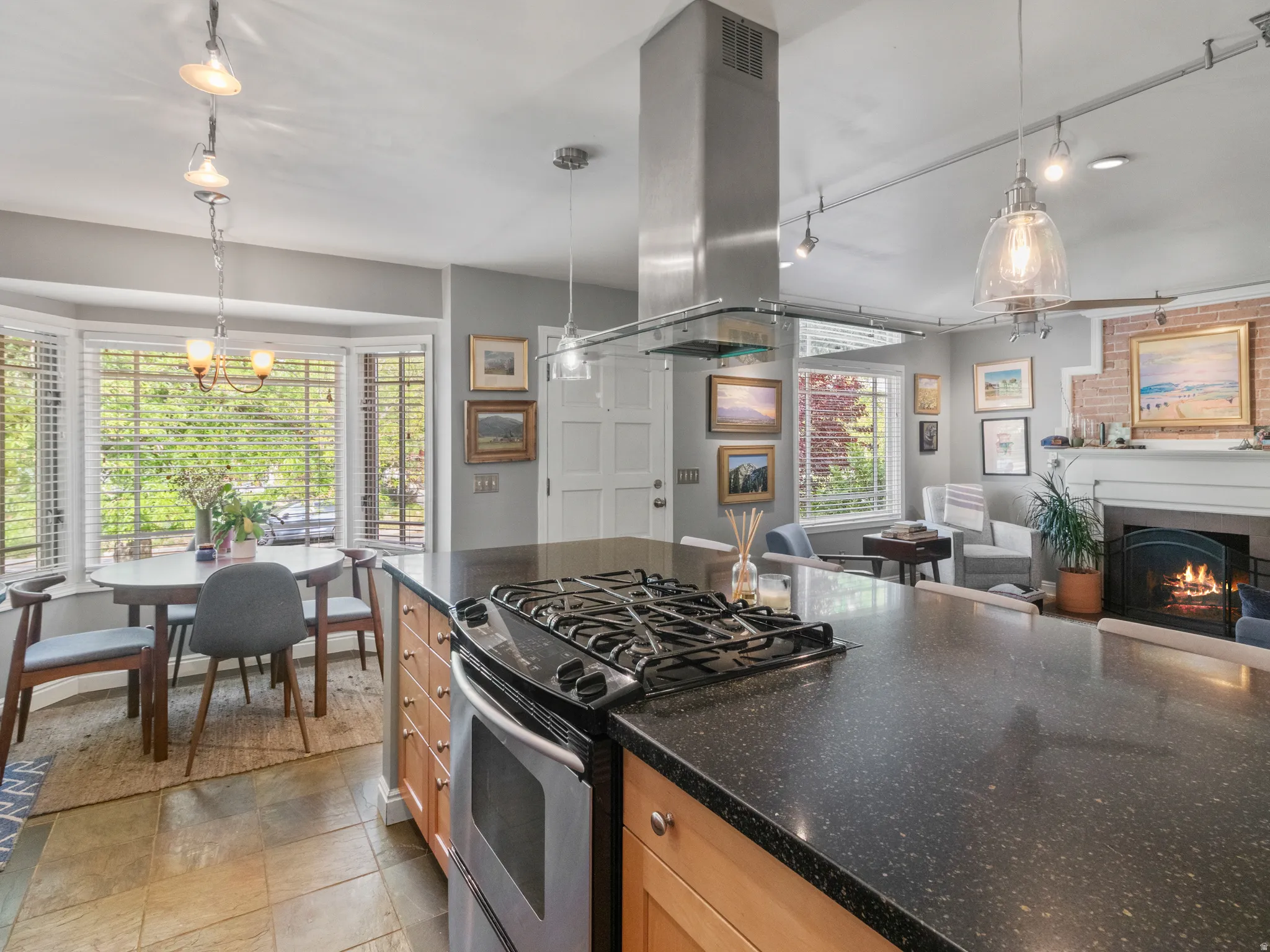 Open-concept kitchen featuring a gas range cooktop, stainless steel range hood, and speckled dark countertops
