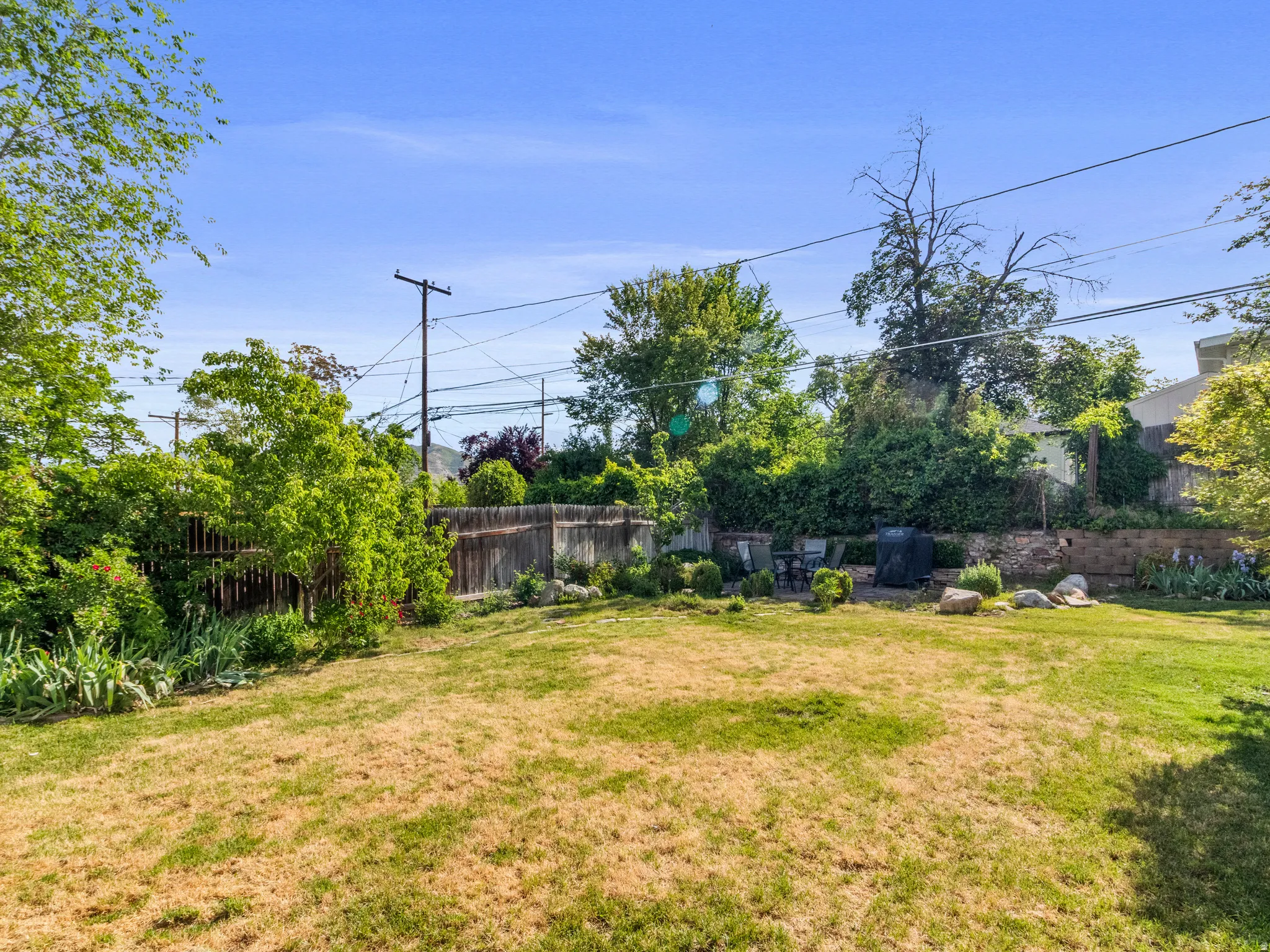 Expansive backyard featuring a partially fenced perimeter and mature perimeter foliage