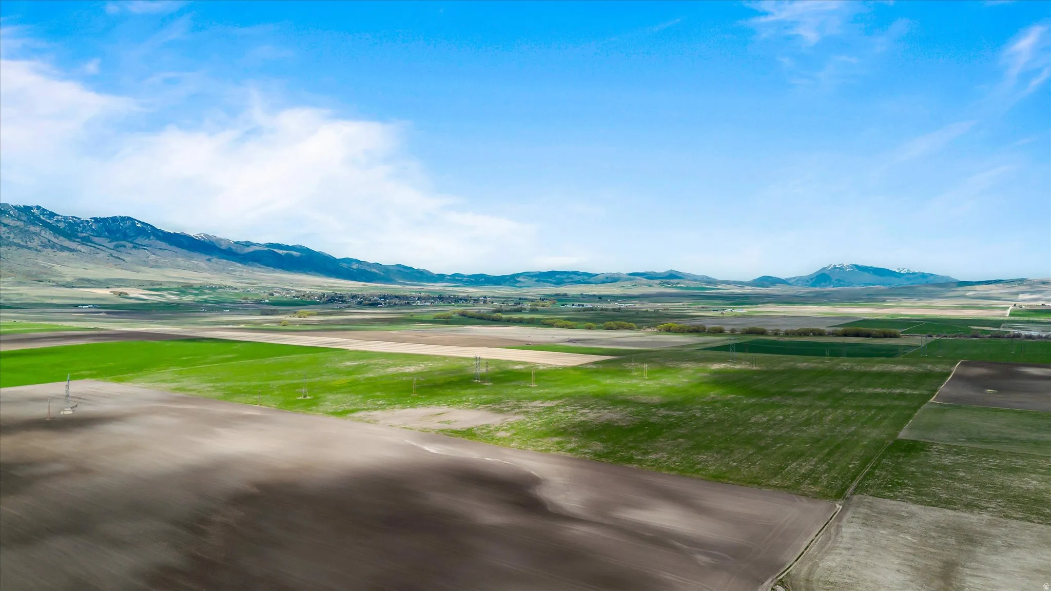 Expansive agricultural land featuring varied cultivated fields and distant mountain ranges