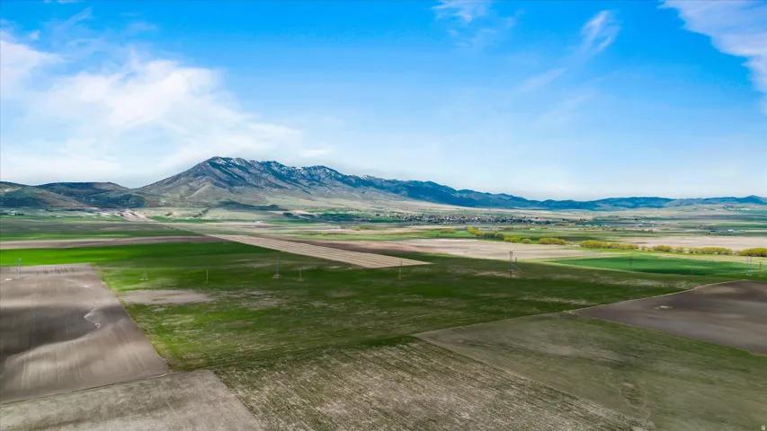 Expansive agricultural landscape featuring large cultivated fields and distant mountainous terrain