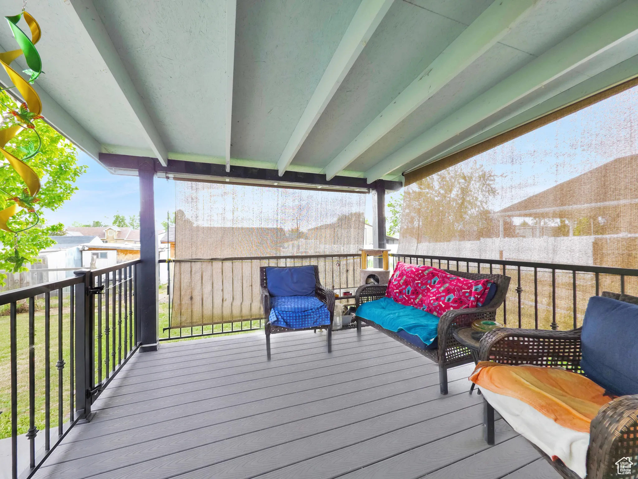 Covered porch featuring wood-finish flooring, black metal railings, and retractable privacy screens
