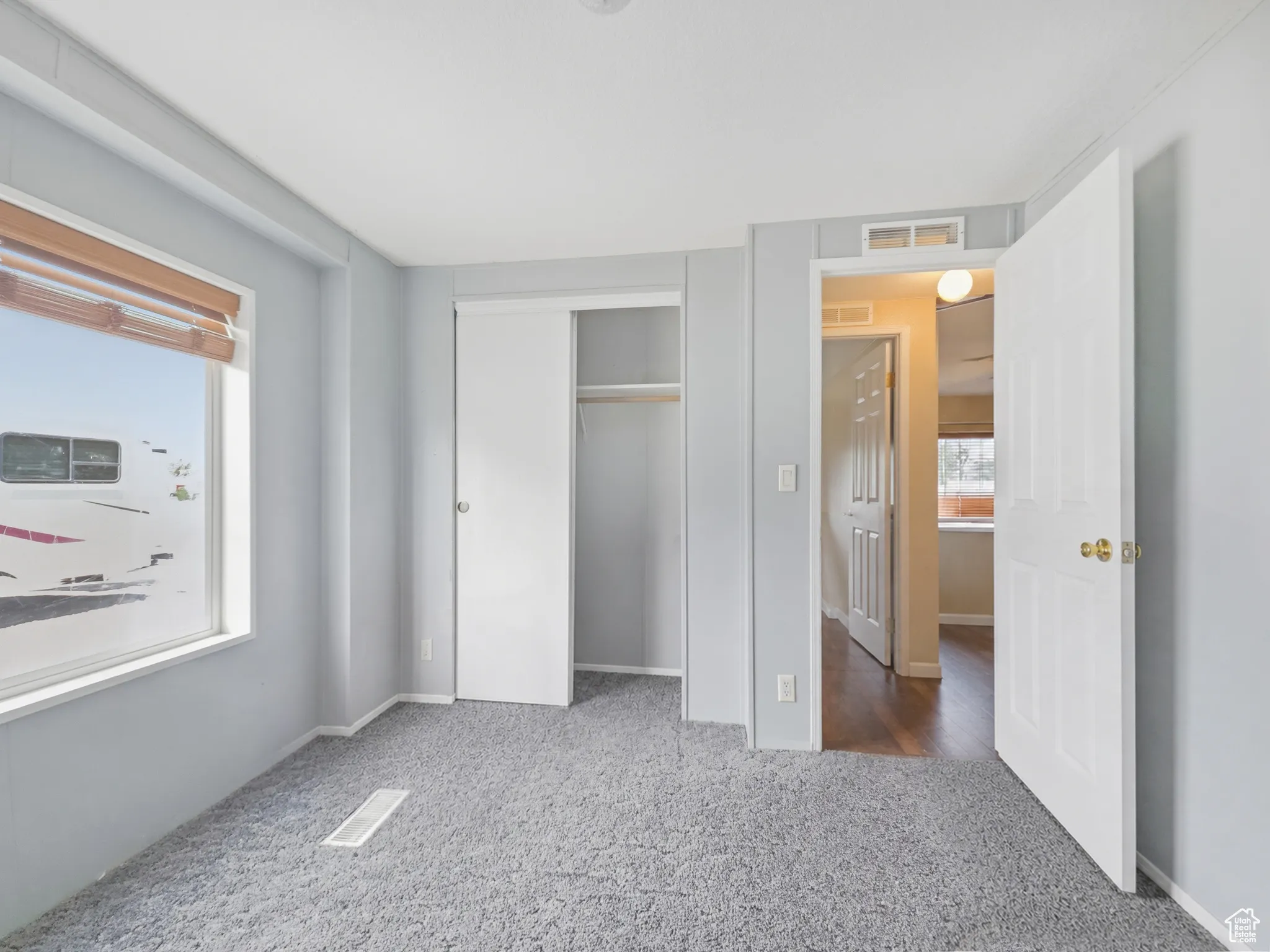 Bedroom featuring light gray wall paint, gray carpet flooring, and a large window with wood-toned blinds