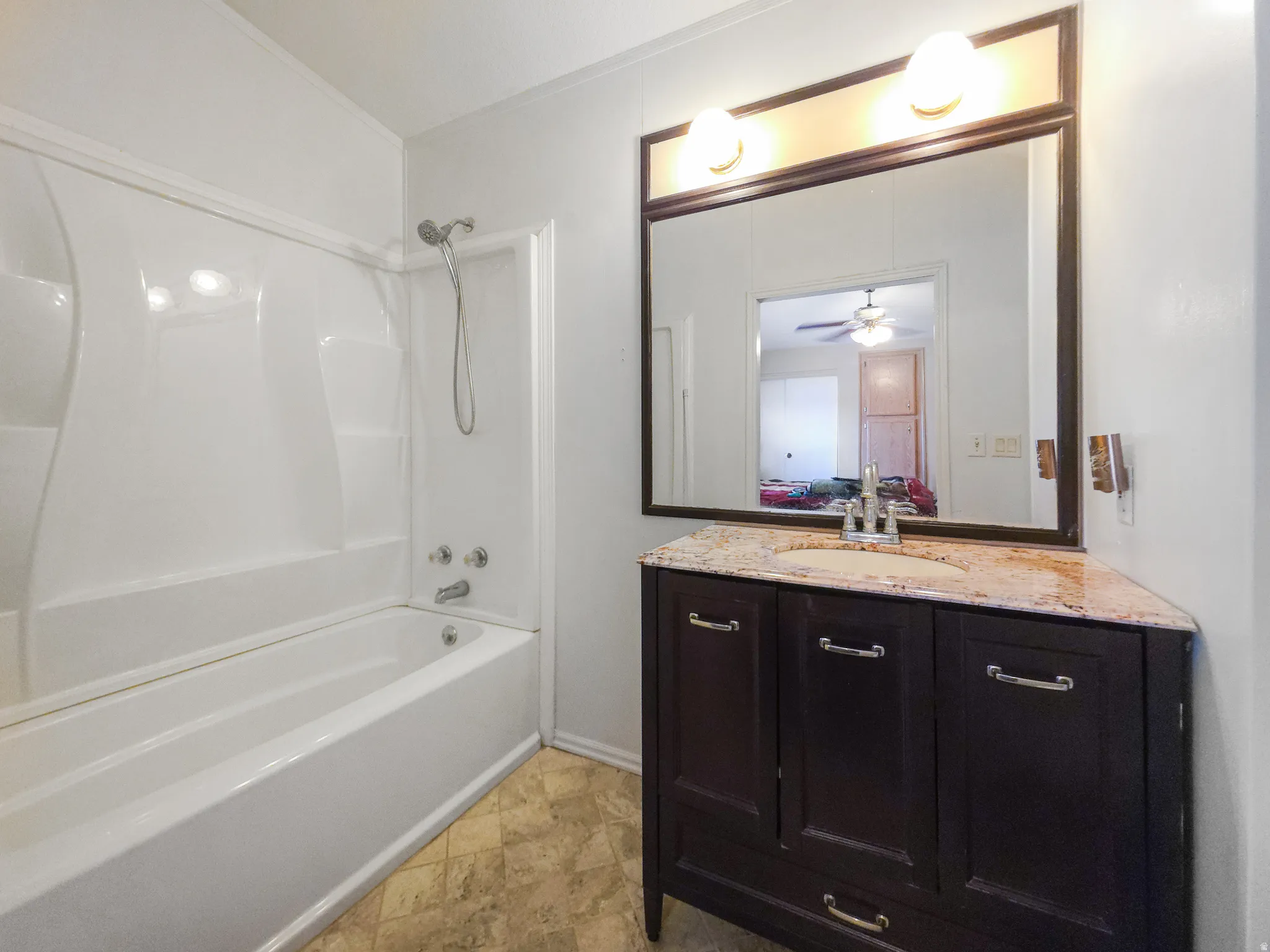 Bathroom featuring a vanity with a light-colored countertop, a dark wood-finish cabinet, and a framed mirror with an overhead light fixture