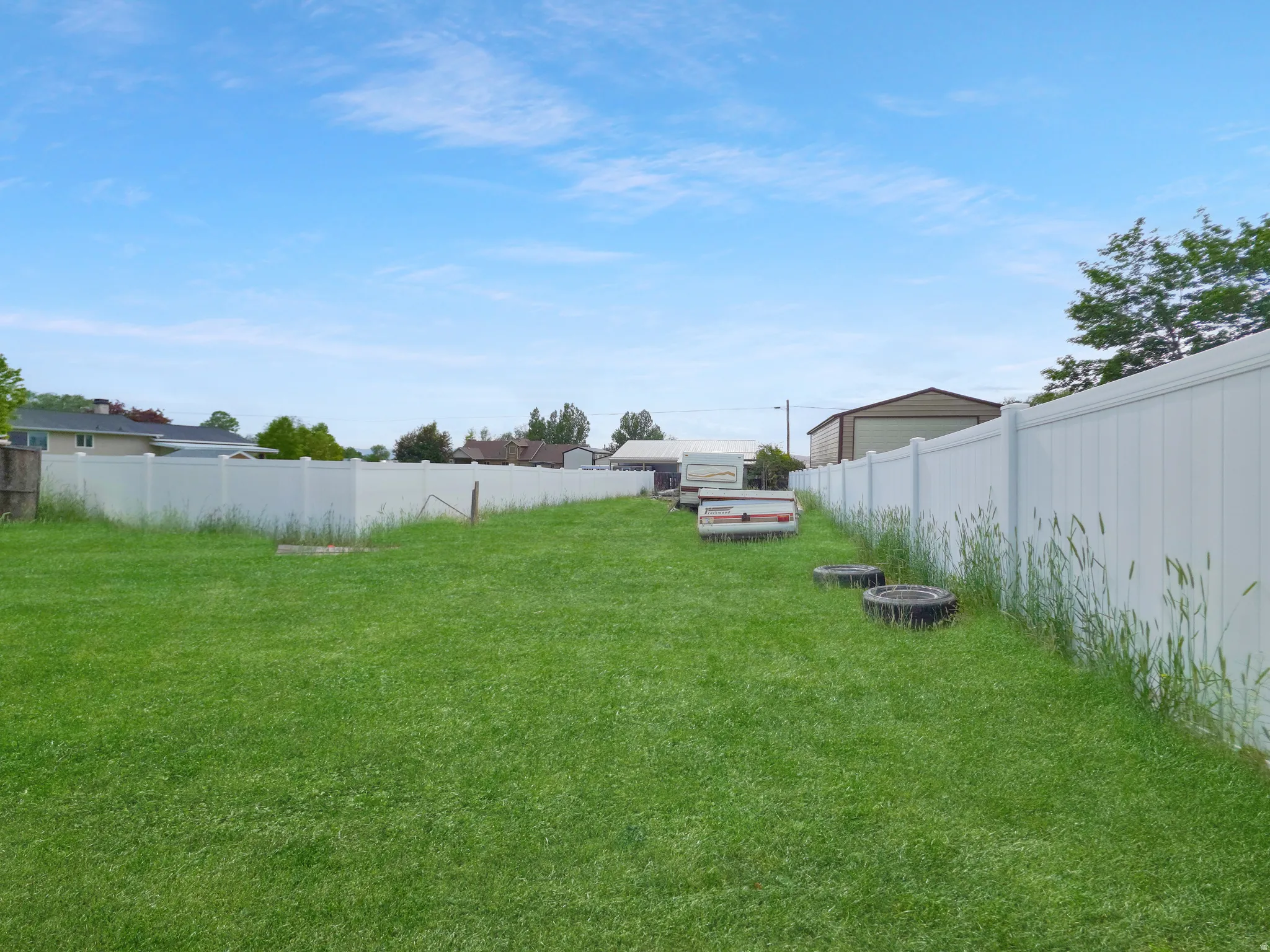 Expansive green lawn with white vinyl fencing enclosing the property