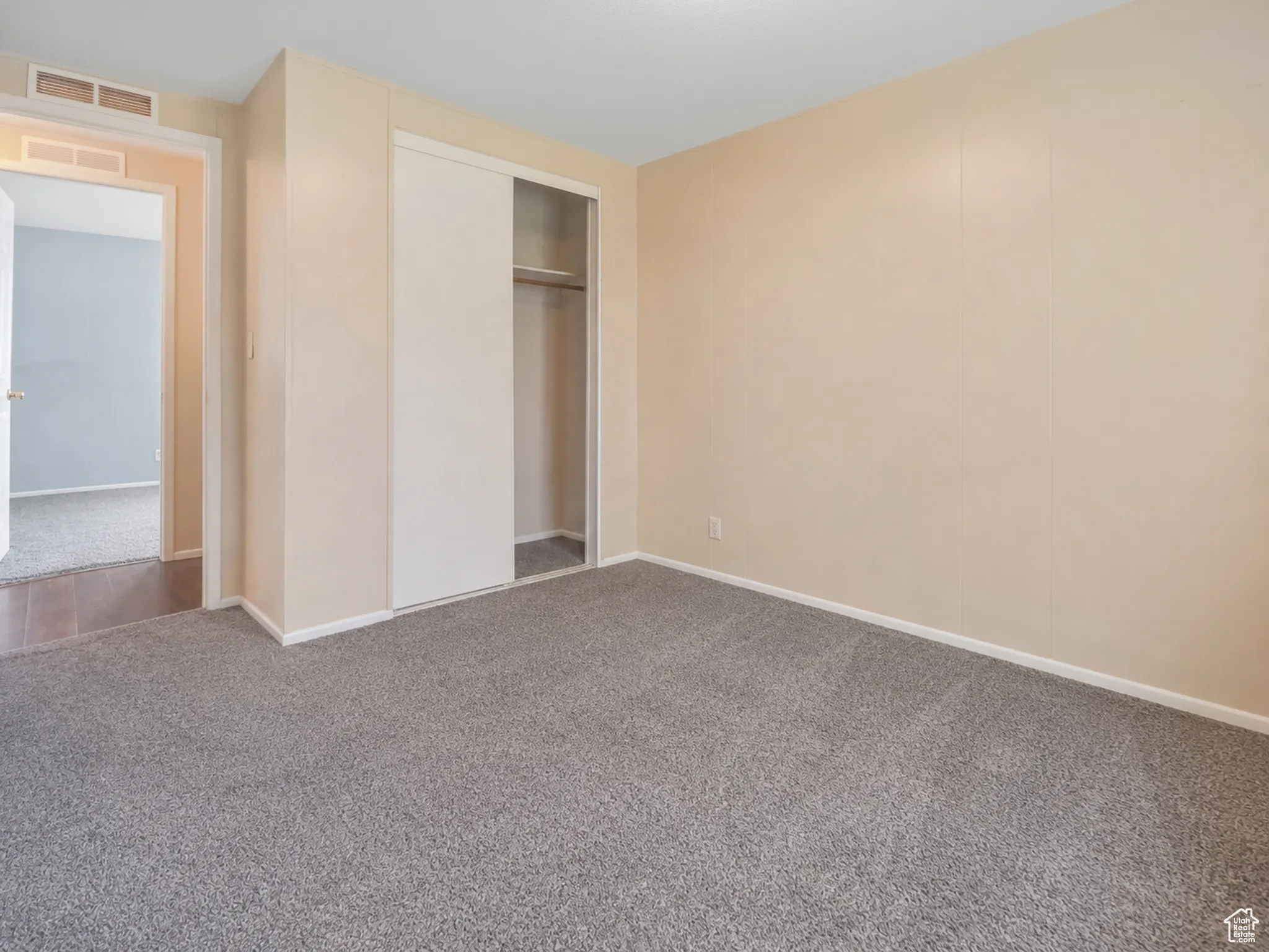Carpeted room featuring a double-door sliding closet with interior shelving and clothing rod