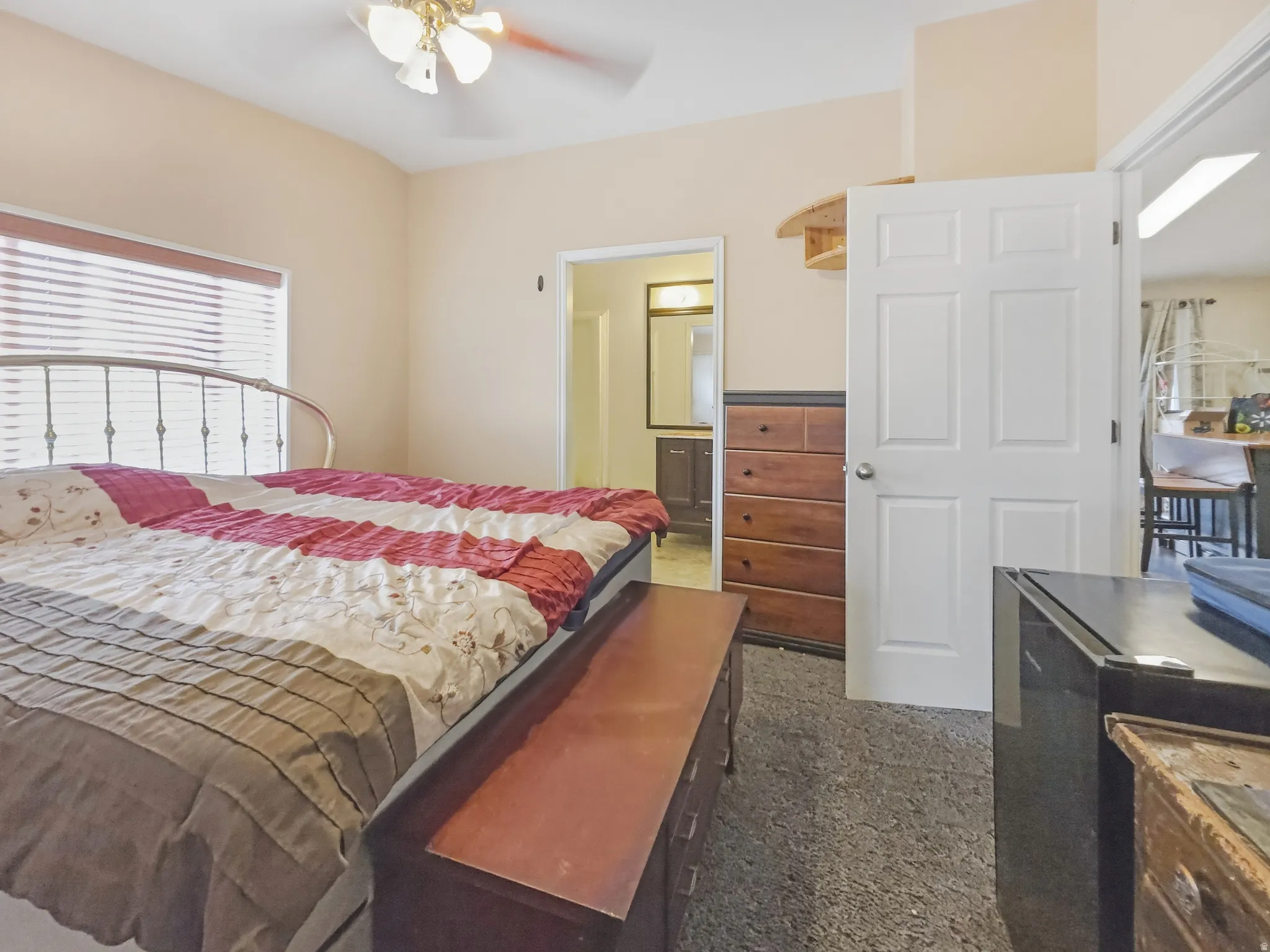 Carpeted room featuring a ceiling fan, window with blinds, and white paneled doors