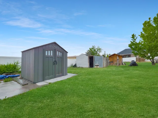 Expansive green space featuring a large storage shed with double doors and a concrete pad