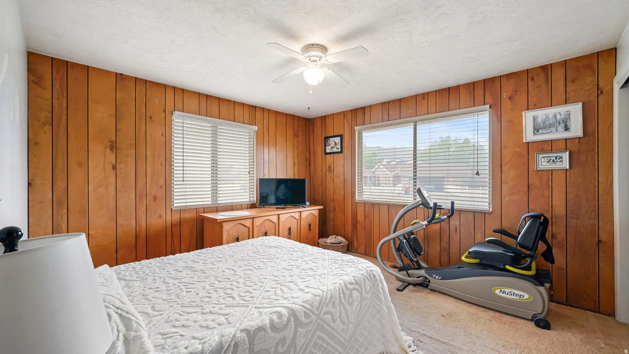 Spacious room featuring wood paneling, a large window with blinds, and ceiling fan