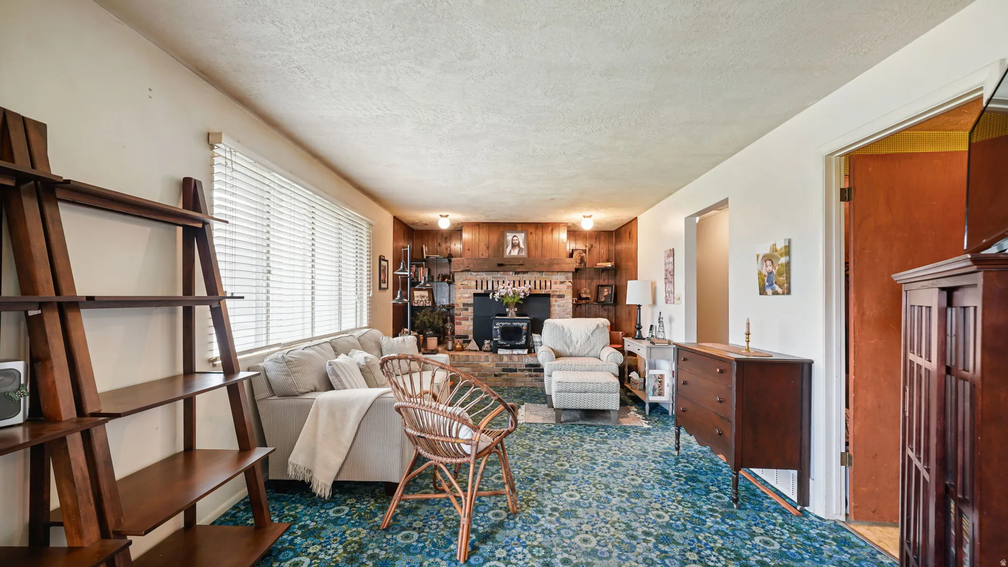 Living area featuring a brick fireplace surround with a wood-paneled accent wall, patterned carpet, and built-in shelving