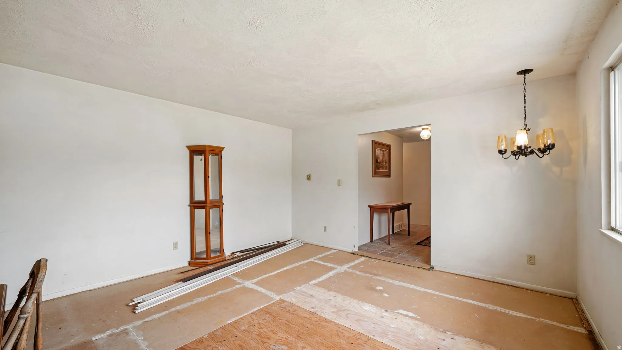 Open room with white walls, a visible window, and a five-light chandelier