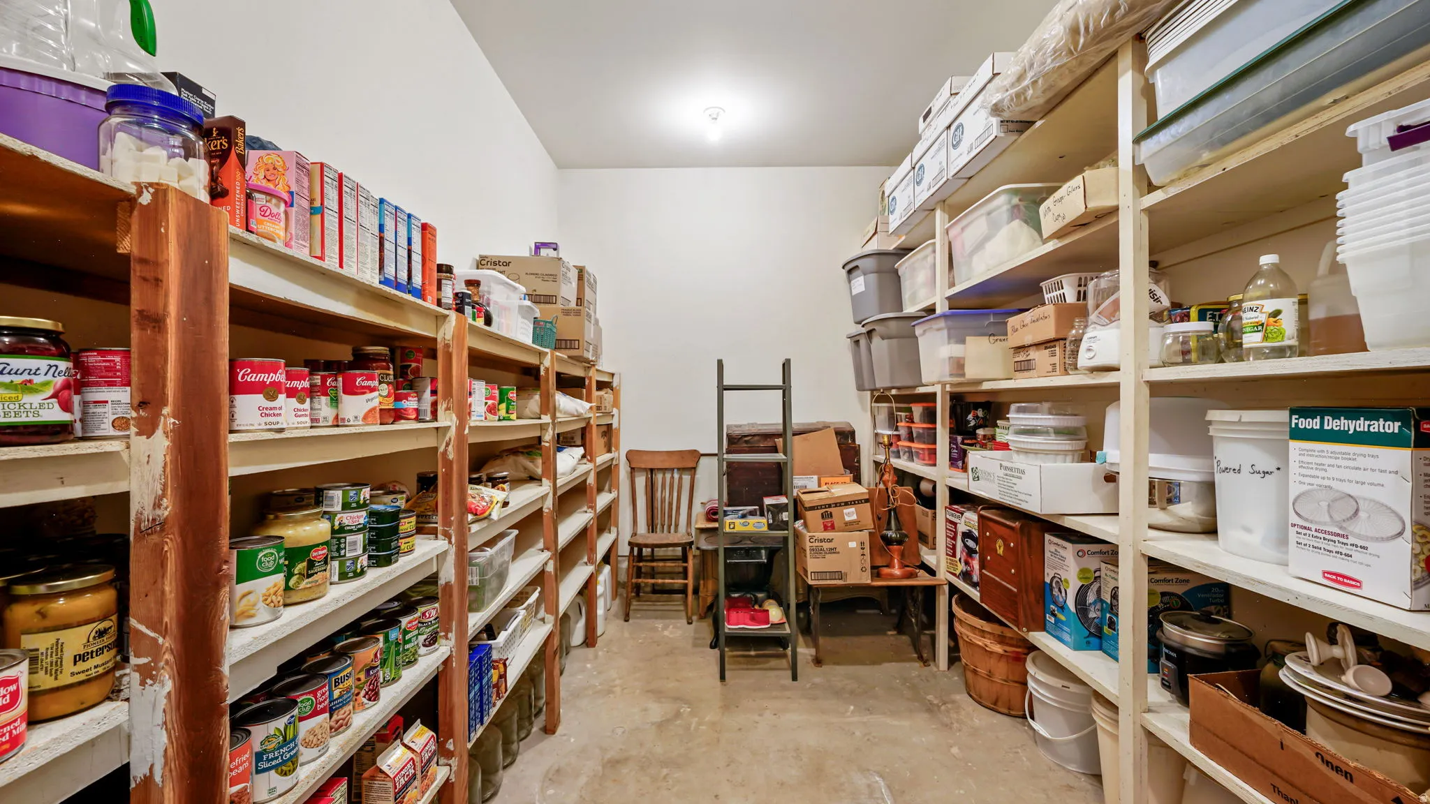 Dedicated storage room featuring extensive built-in shelving, white walls, and overhead lighting
