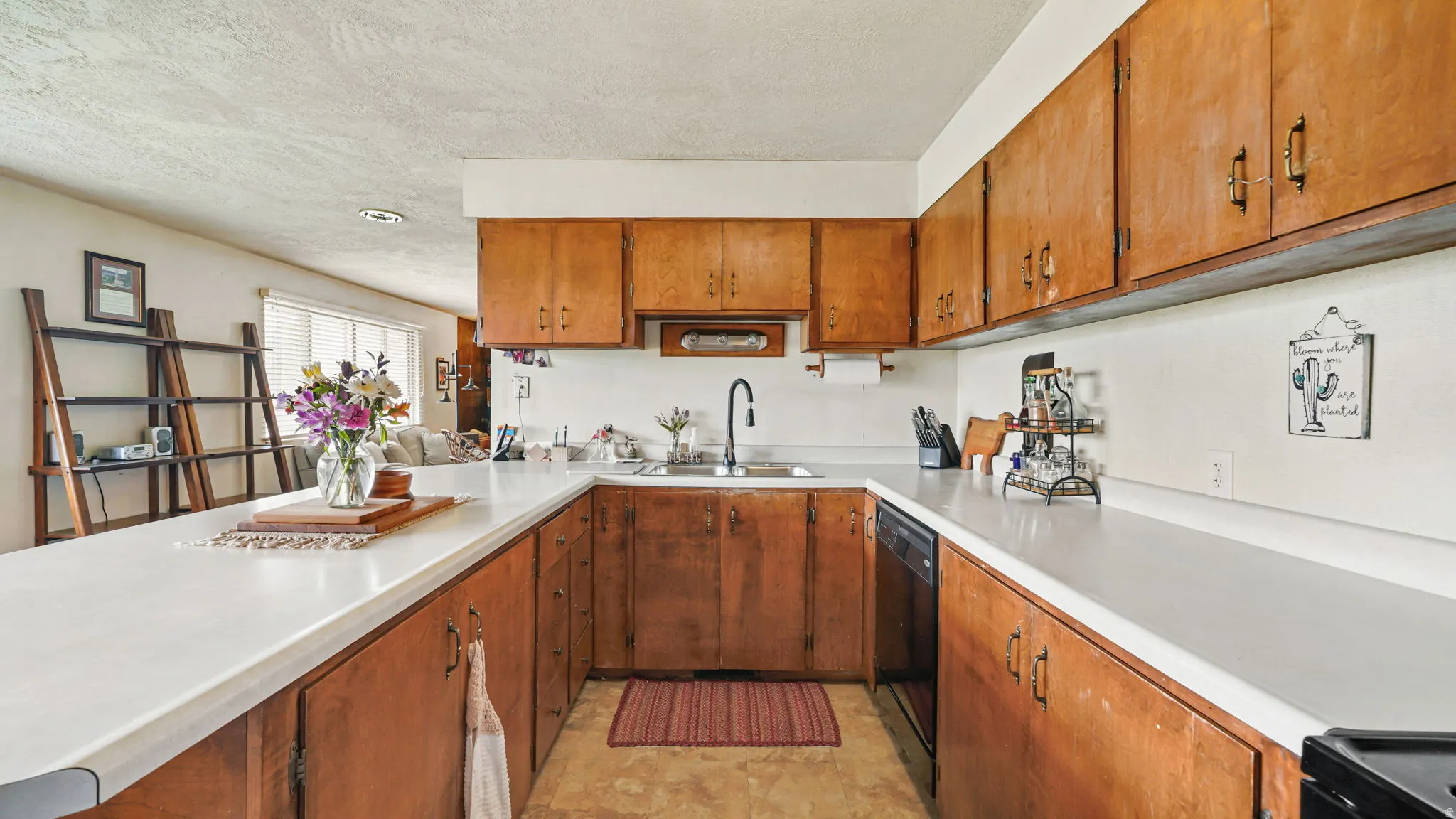U-shaped kitchen featuring light wood cabinetry, white countertops, and a stainless steel sink with a matte black faucet