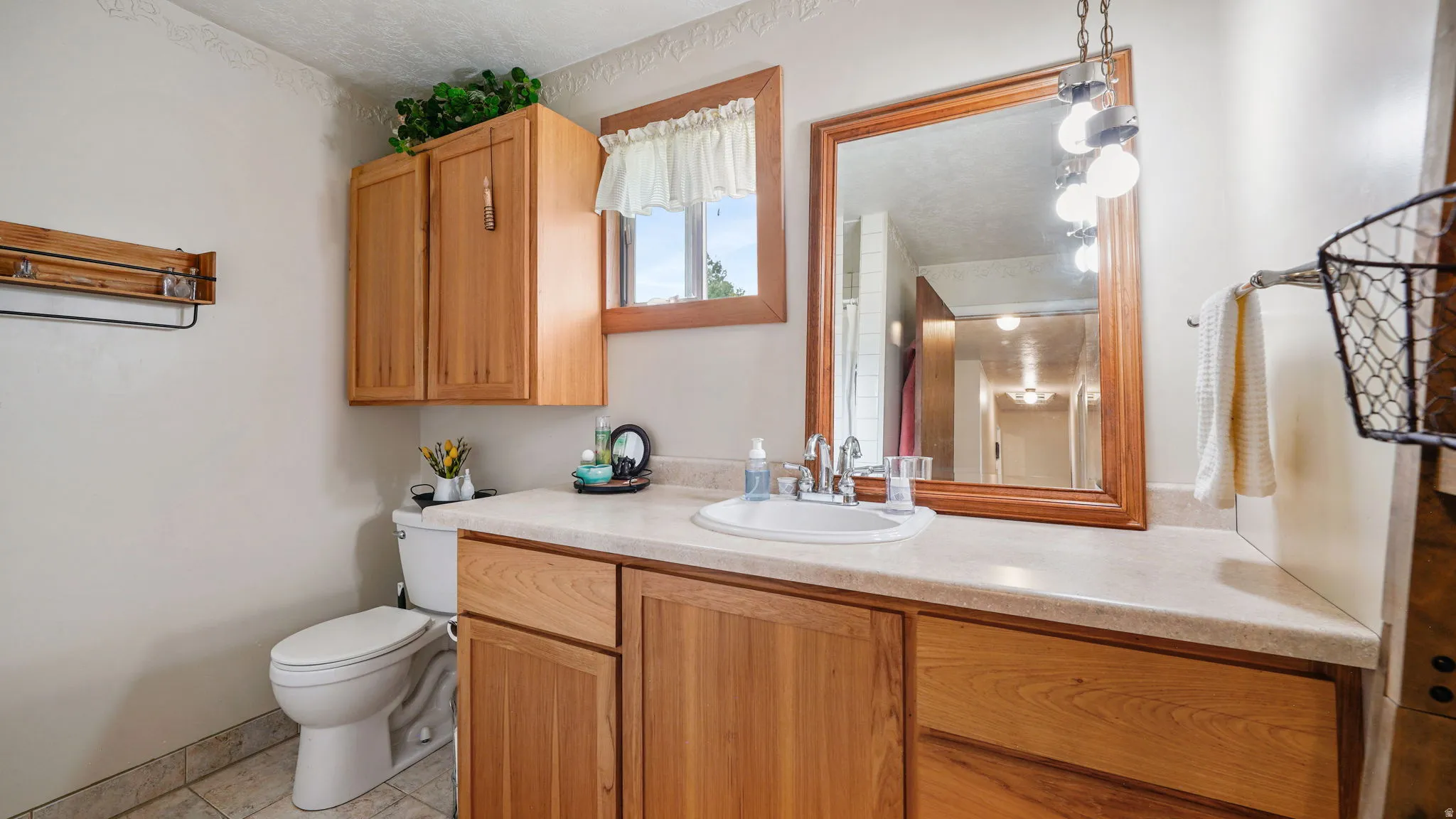 Bathroom featuring a wood-finish vanity with an integrated sink and light-toned countertop