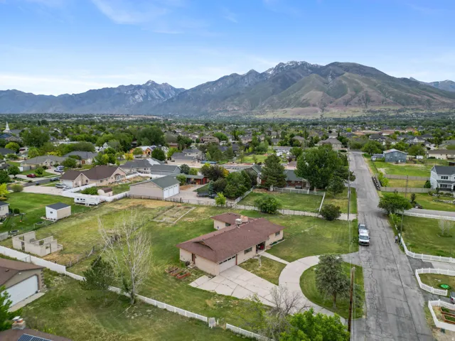 Expansive lot featuring a single-story residence with a brown roof and a white picket fence perimeter