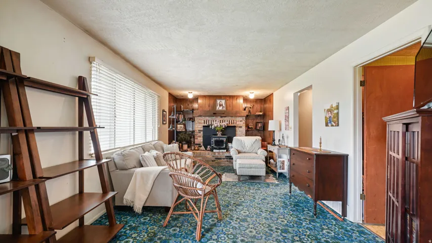 Living area featuring a brick fireplace surround with a wood-paneled accent wall, patterned carpet, and built-in shelving