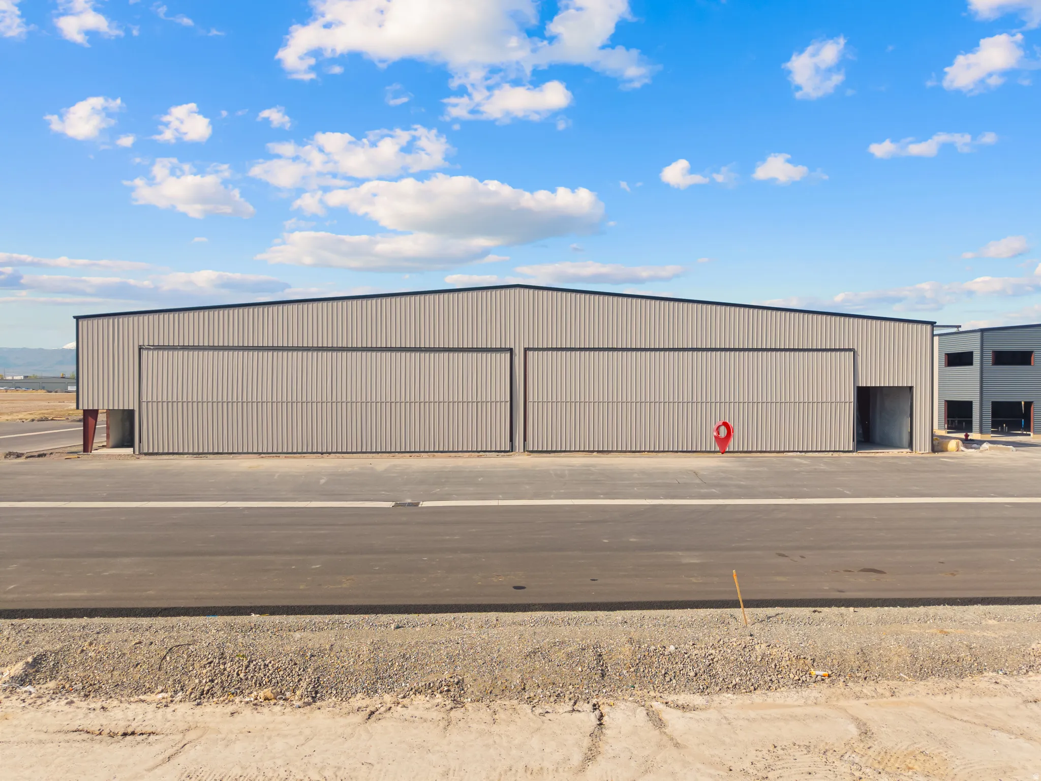 Industrial hangar building featuring a metal panel exterior and a black pitched roofline