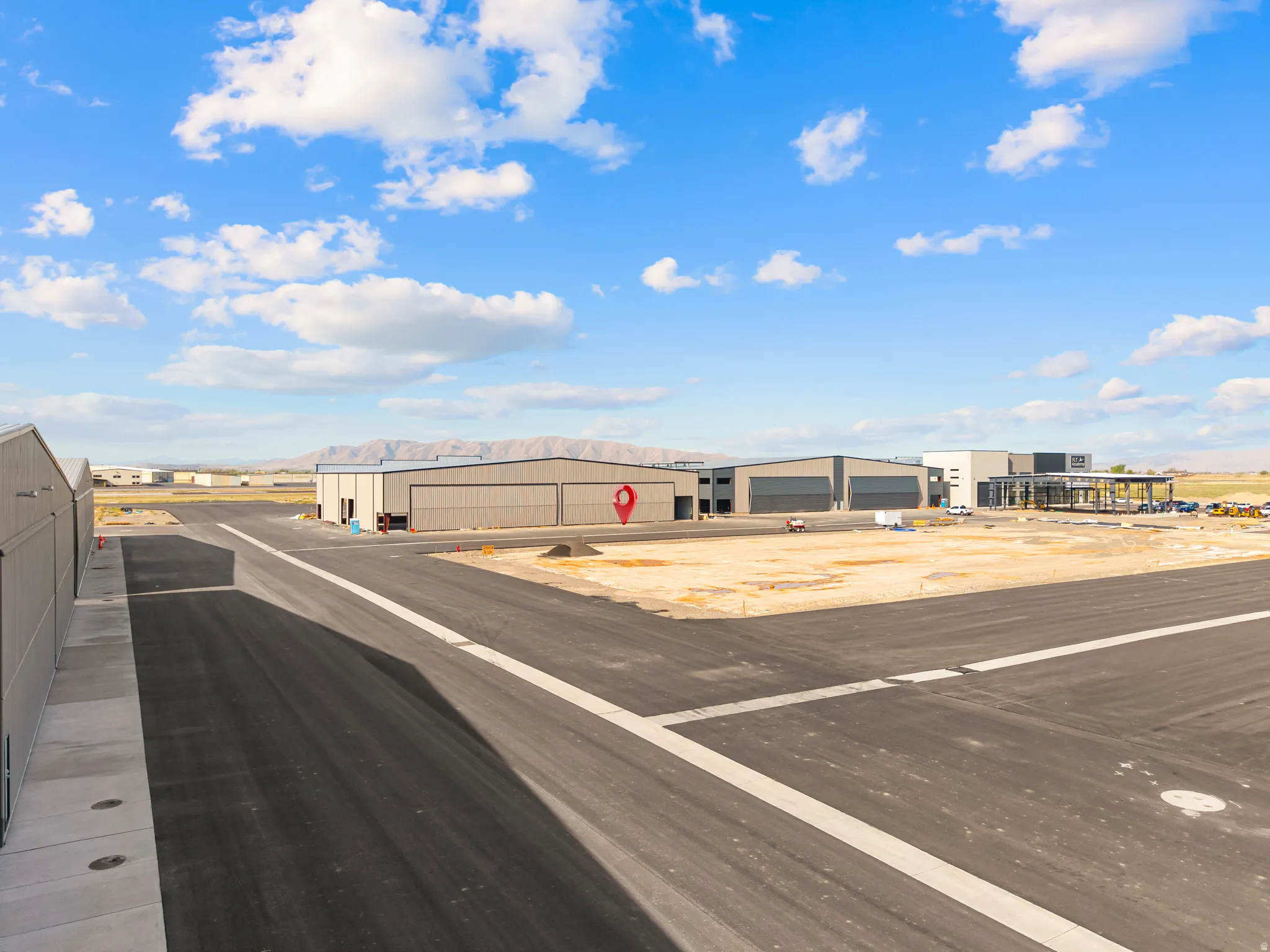 Asphalt taxiway with white markings providing direct access to multiple aircraft hangars