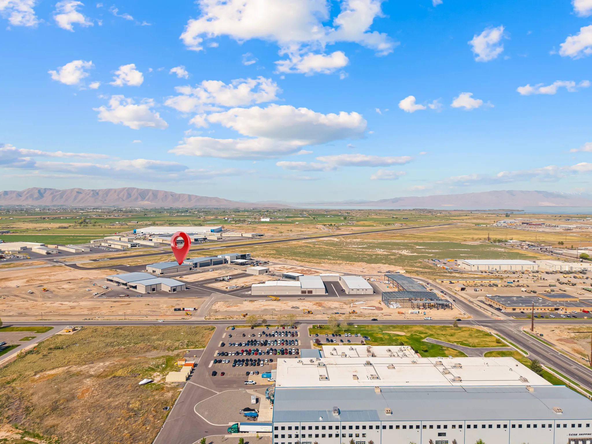 Aerial perspective showcasing multiple industrial properties, expansive flat land, and distant mountains