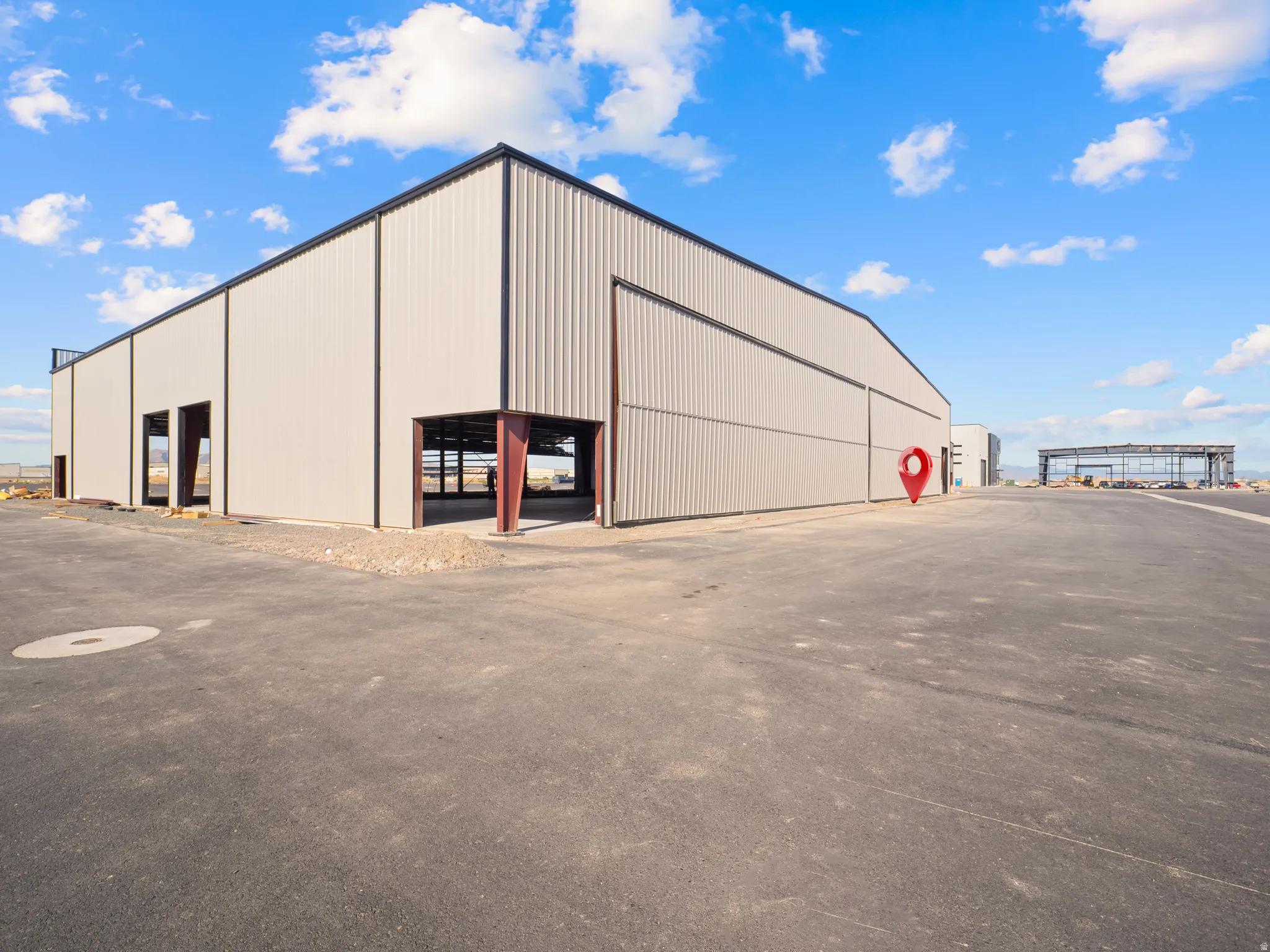 Large industrial building featuring corrugated metal siding, black trim, multiple bay openings, and a spacious asphalt lot