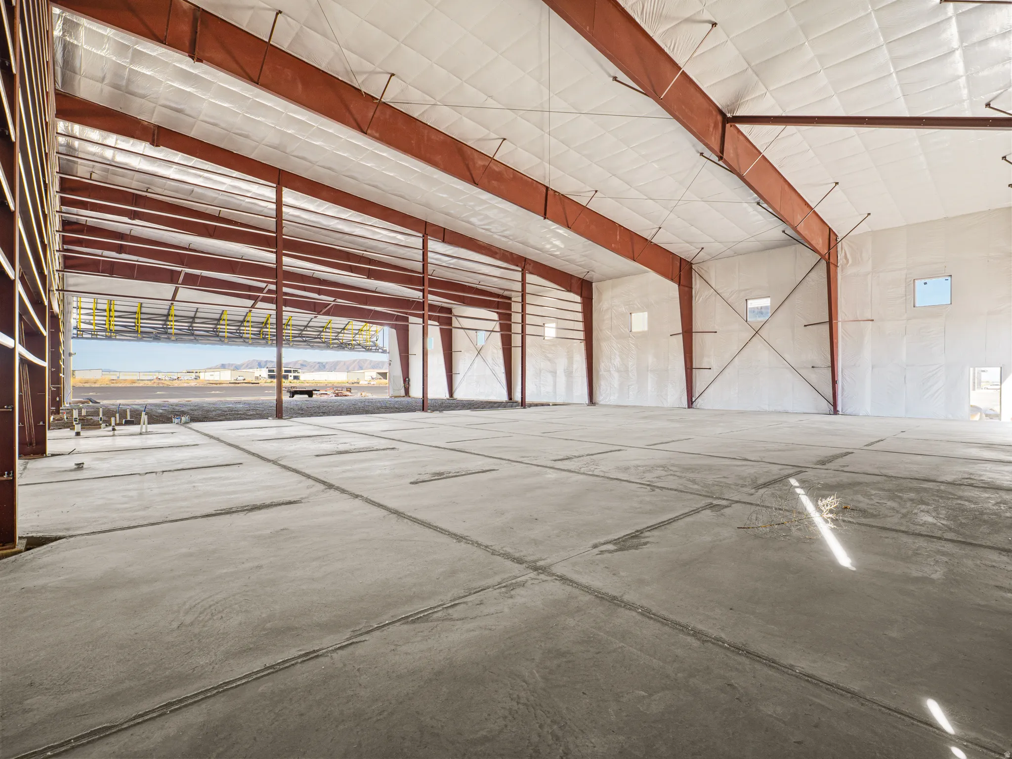Spacious industrial interior featuring a concrete floor, exposed structural steel beams, and insulated panel walls