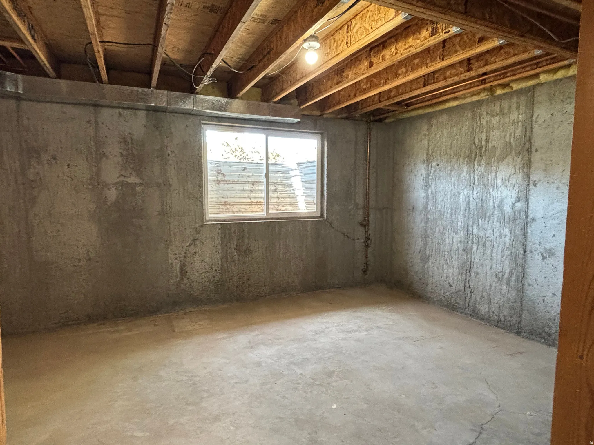 Unfinished basement space with exposed concrete walls and floor