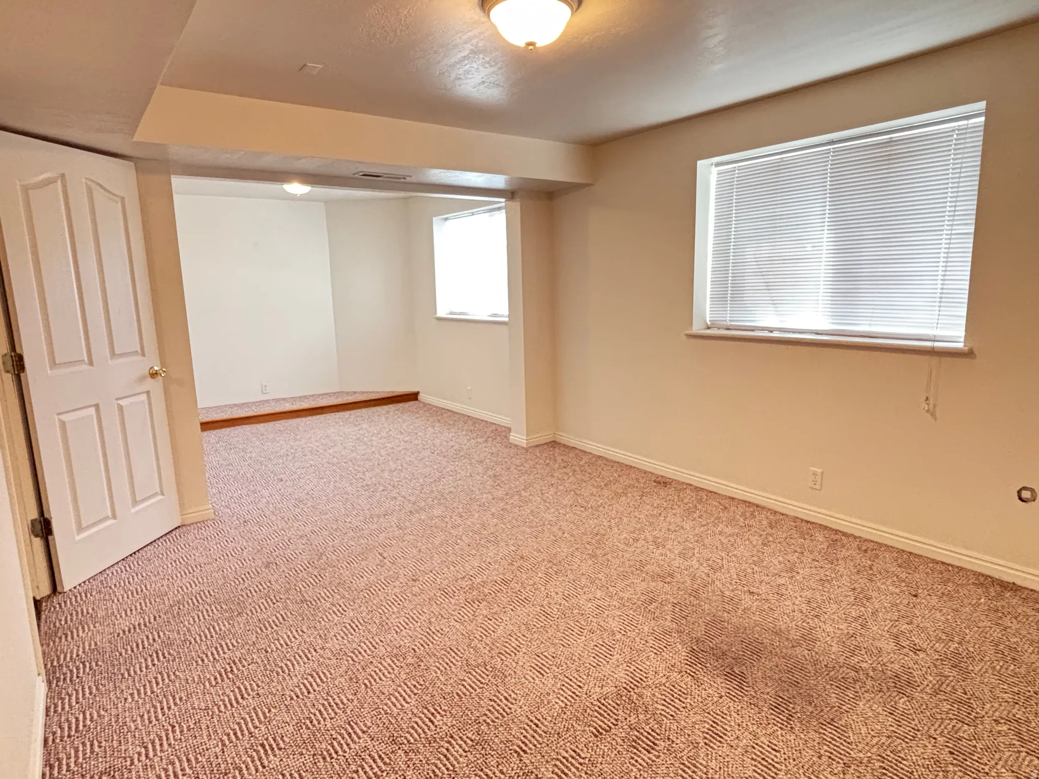 Spacious interior room featuring patterned carpeting and neutral wall paint