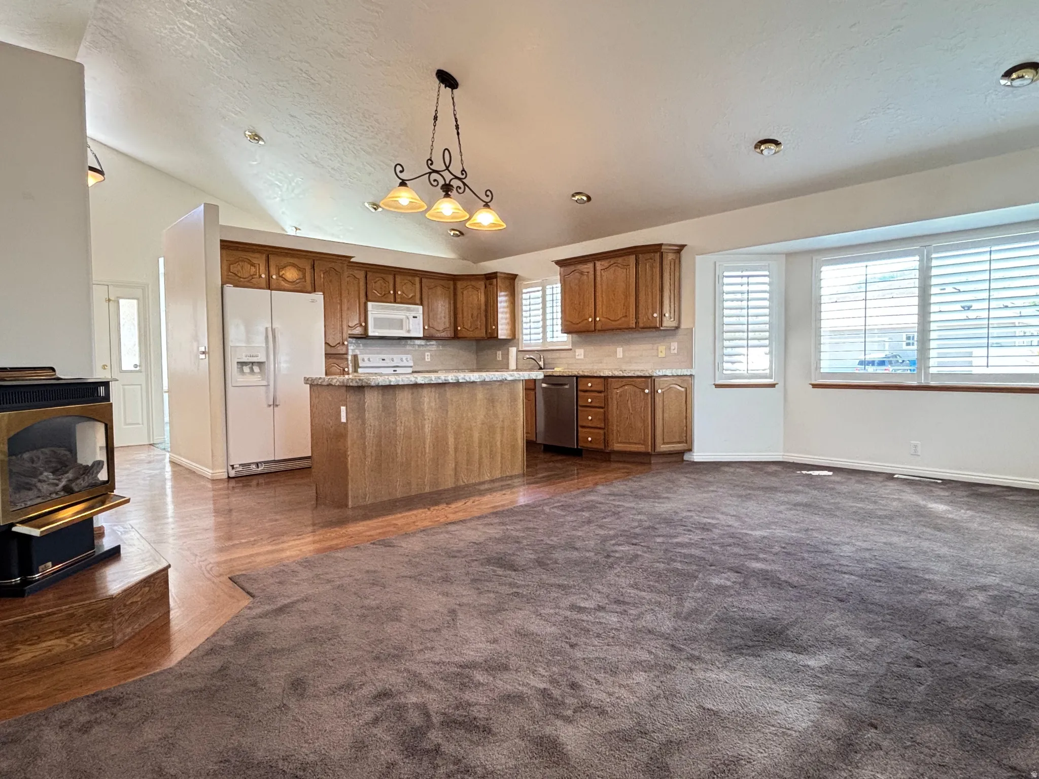 Open-concept living area featuring a kitchen with wood cabinetry, light-toned countertops, and a central island