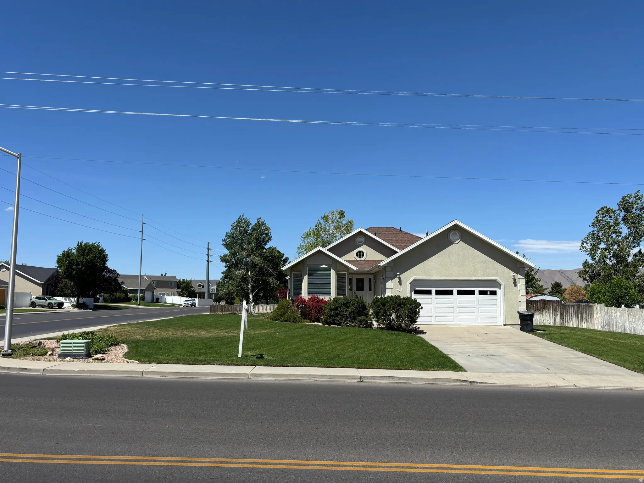 Stucco exterior residence with an attached two-car garage, a well-maintained front lawn, and mature landscaping