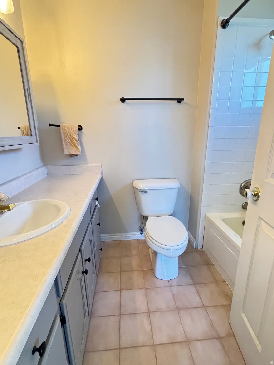 Bathroom featuring a single vanity with light-toned countertop, a drop-in sink, and painted cabinetry with dark hardware
