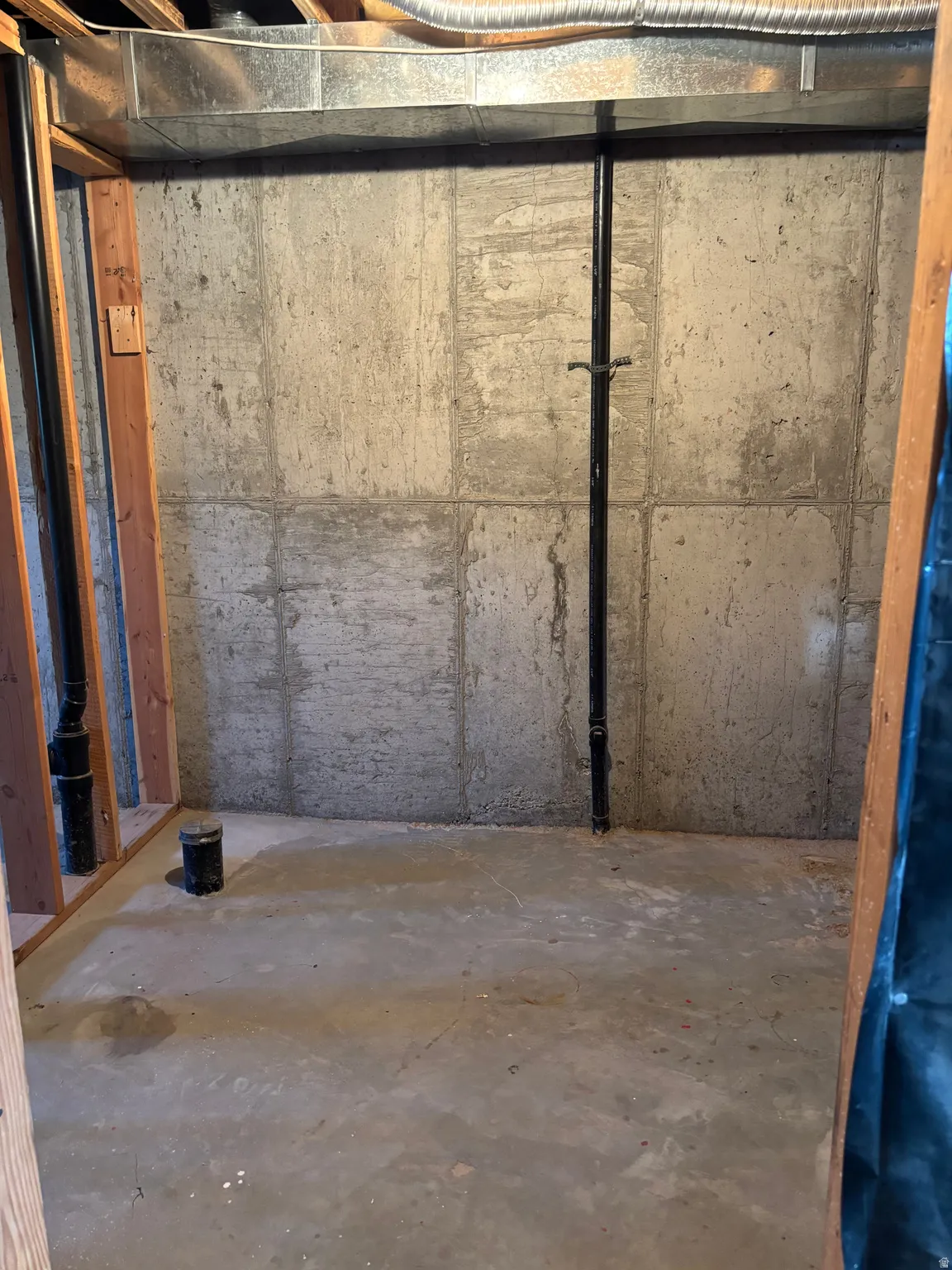 Unfinished basement space featuring concrete block walls and a concrete floor