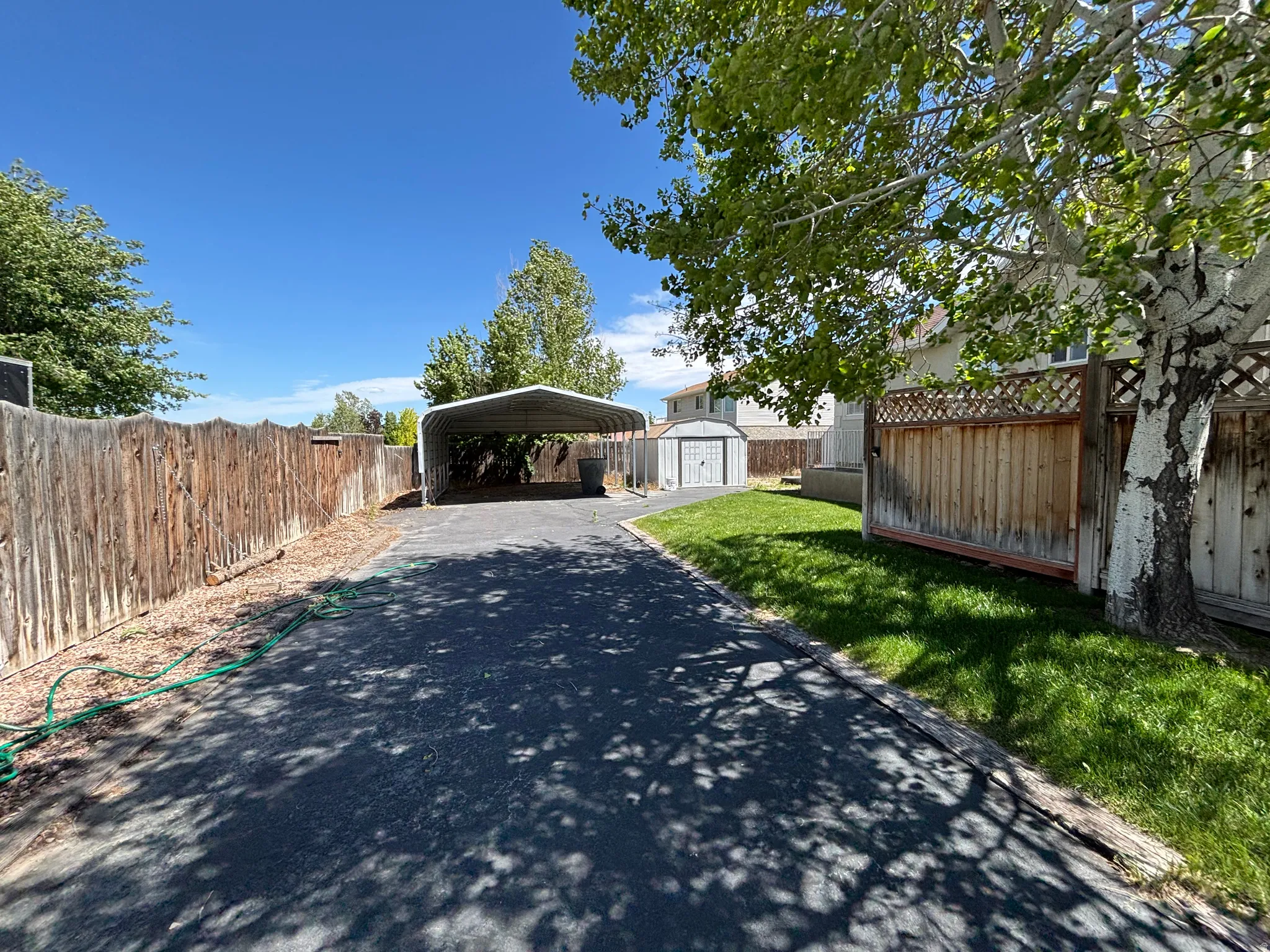 Paved driveway offering vehicle access, accompanied by a metal carport structure