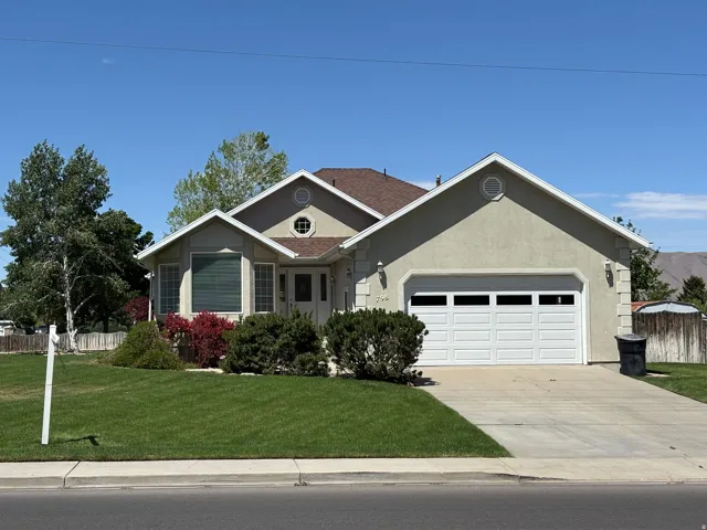 Single-story residence featuring stucco exterior and a two-car garage with panel windows