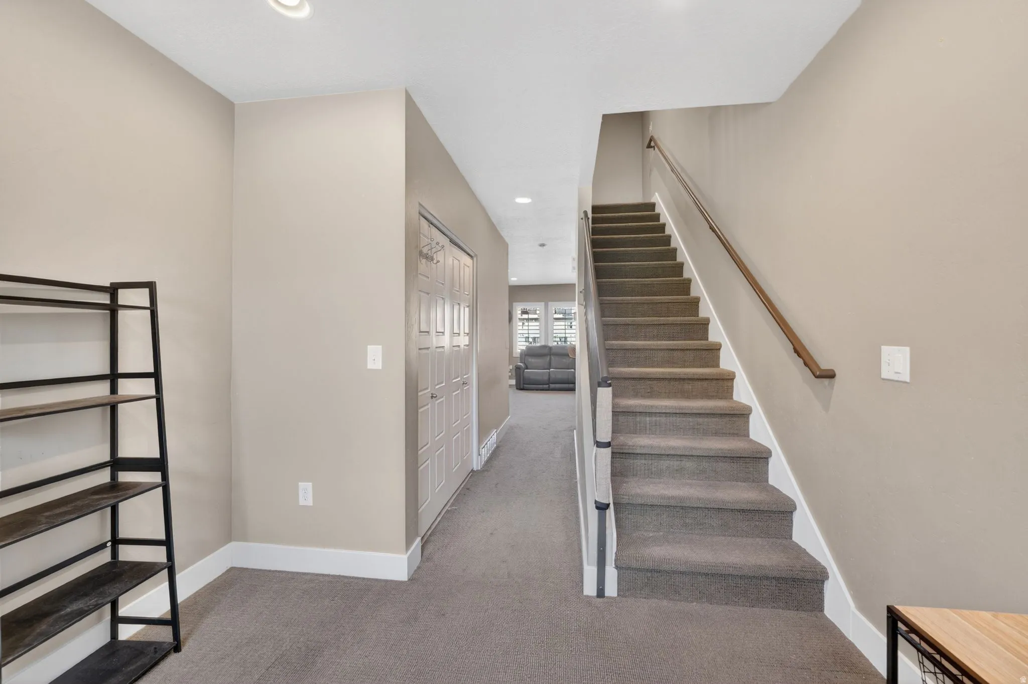 Carpeted staircase with a wood-finish handrail and contrasting white risers