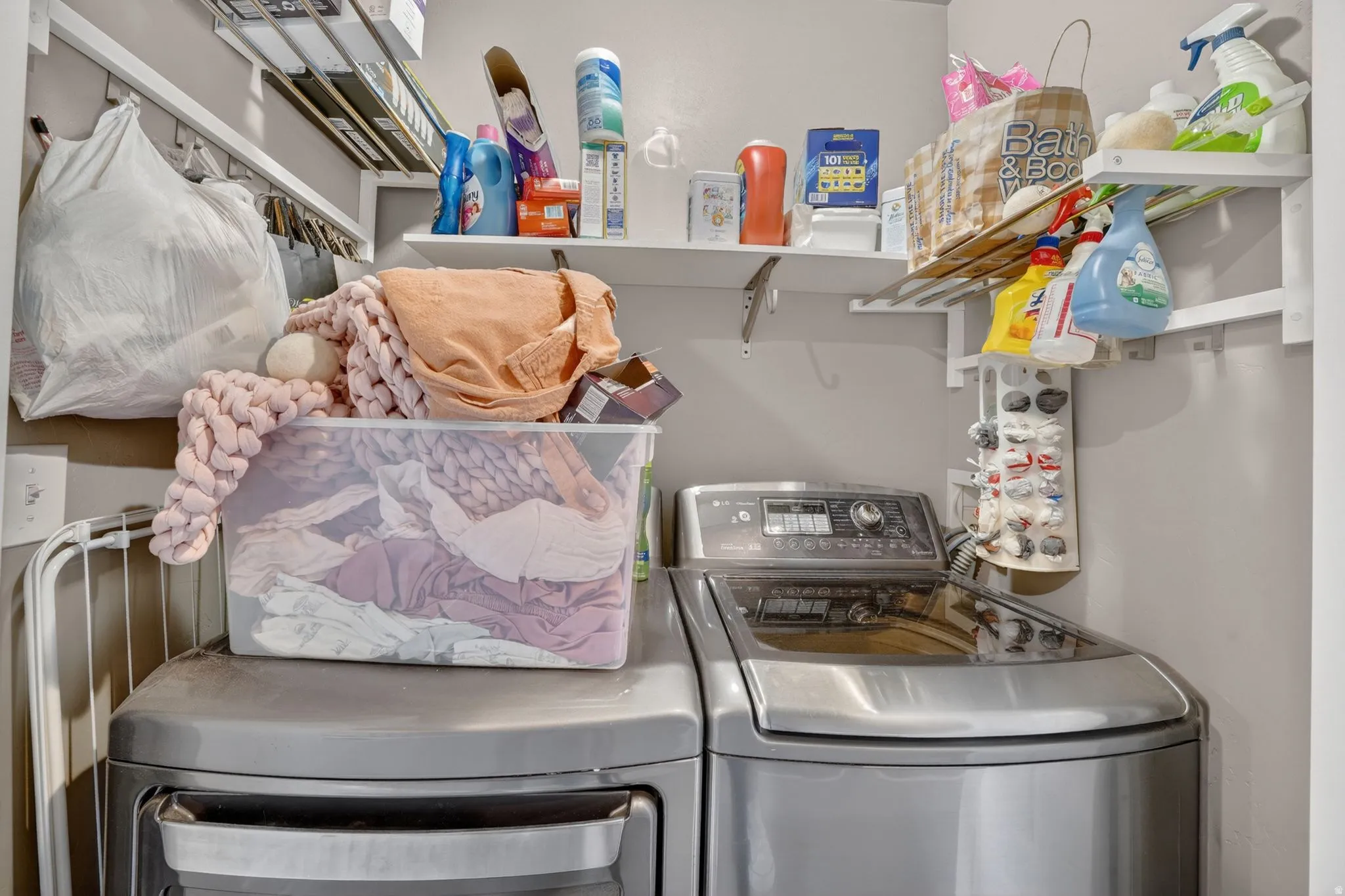 Laundry area featuring stainless steel finish appliances, wall-mounted shelving, and light gray wall paint